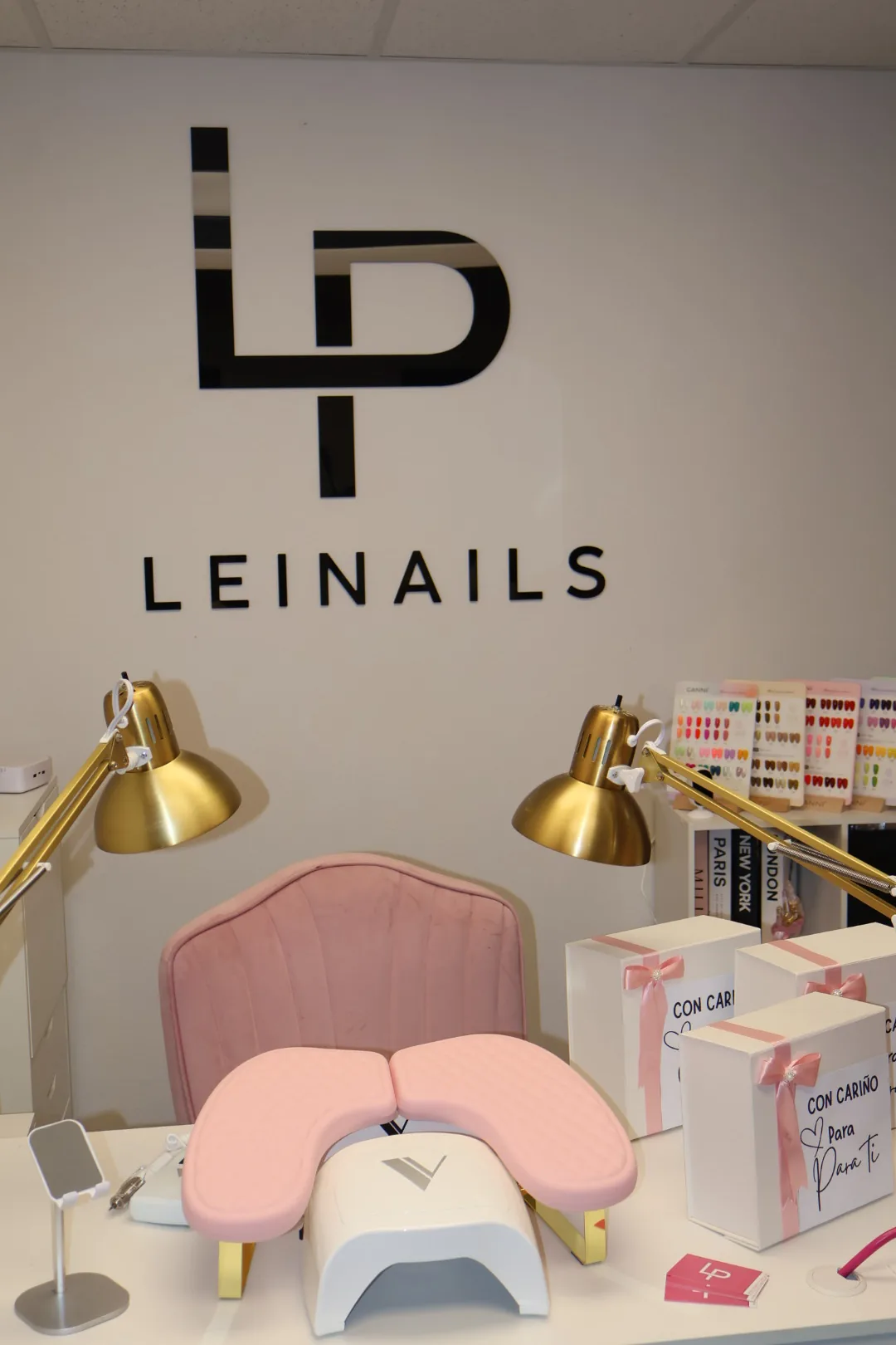 The LEINAILS logo on the studio wall, above the manicure station with gold lamps.