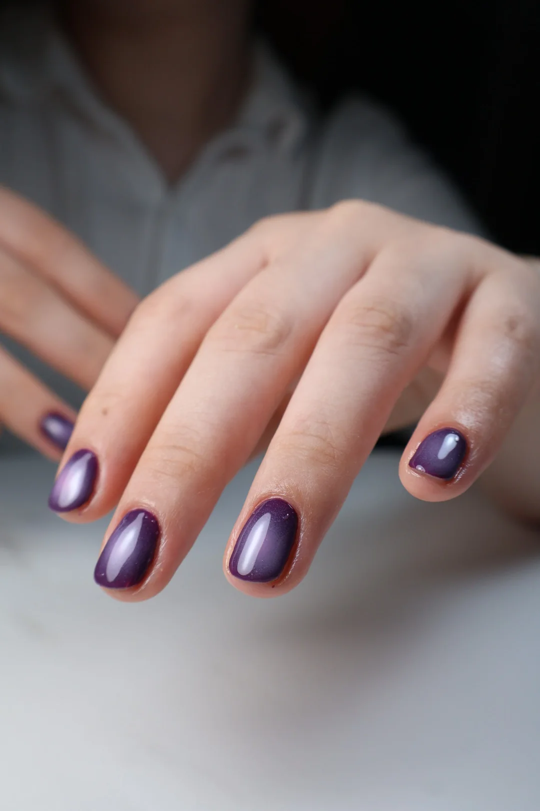 Manicura en tono violeta metalizado sobre uñas cortas.