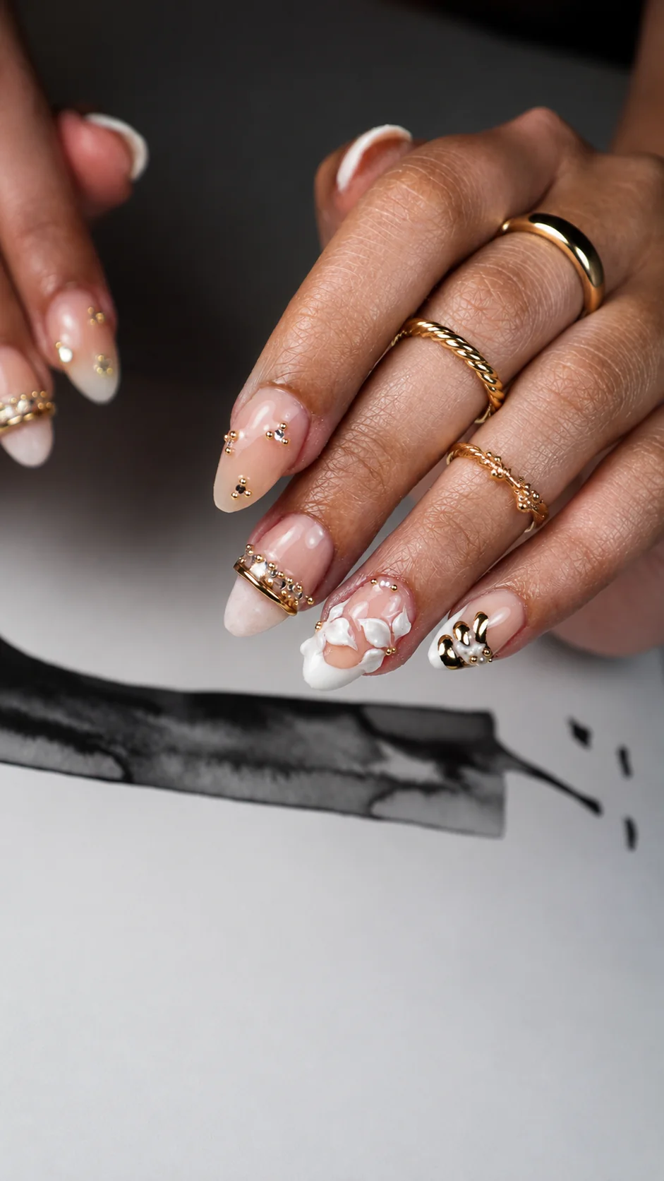 Uñas largas con relieve floral y detalles dorados.