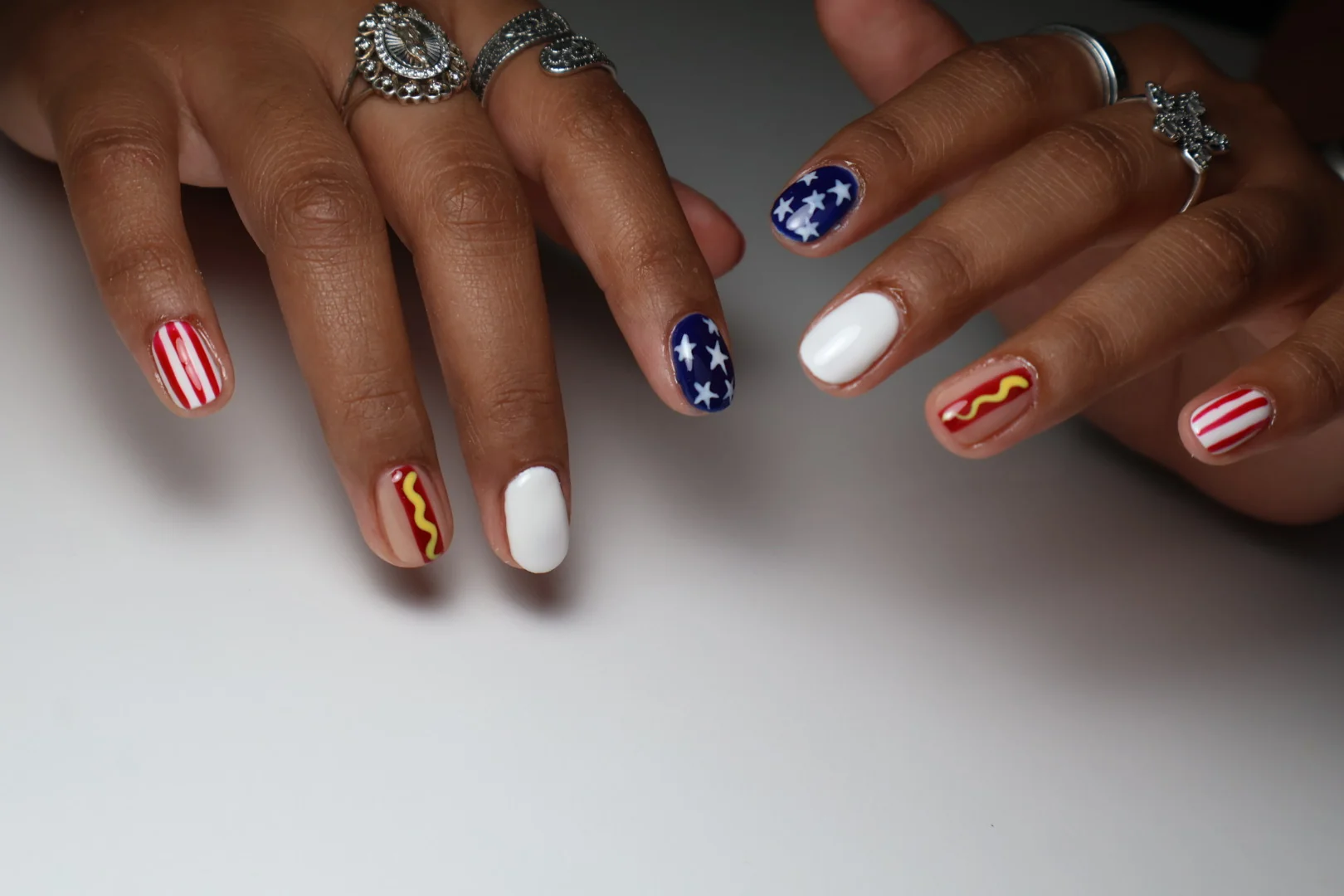 Uñas con estrellas sobre azul y diseños distintos en cada dedo.