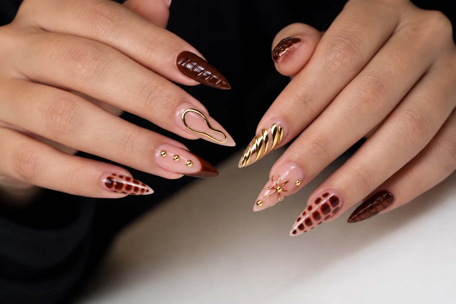 Brown and nude stiletto nails with gold relief and rhinestones.